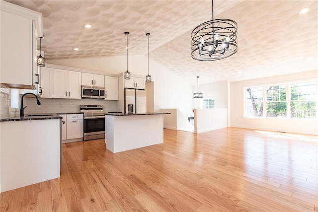 kitchen with appliances with stainless steel finishes, light wood finished floors, a sink, white cabinetry, and a center island