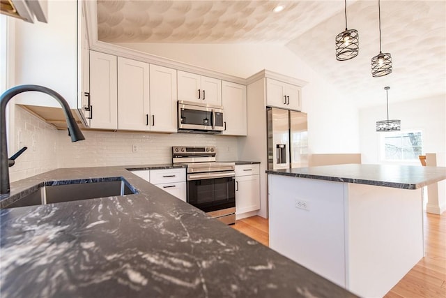 kitchen with lofted ceiling, a sink, appliances with stainless steel finishes, a center island, and light wood-type flooring