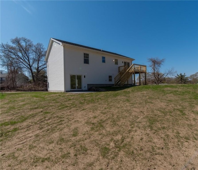 back of property featuring a lawn, a deck, and stairway