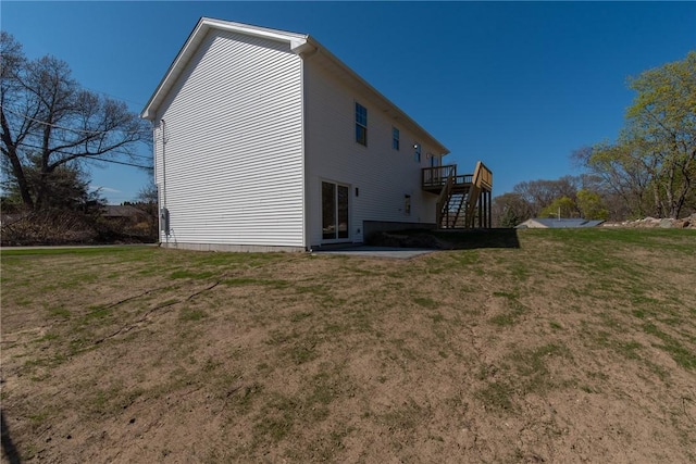 back of house featuring a lawn, stairs, and a wooden deck