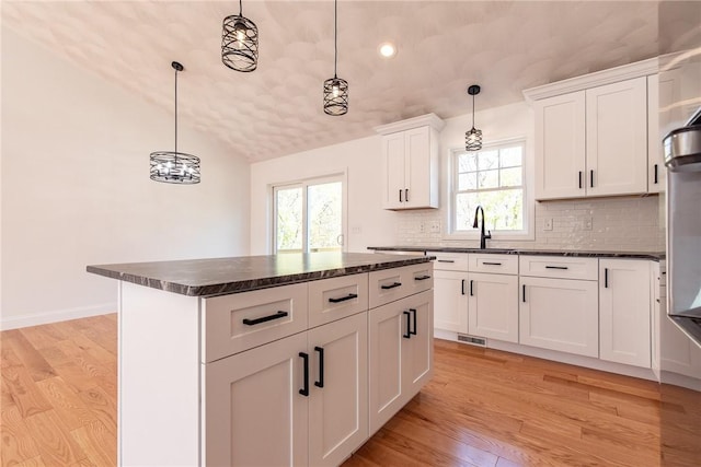 kitchen with light wood-type flooring, visible vents, decorative backsplash, and a healthy amount of sunlight