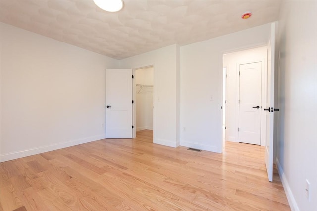 empty room with baseboards, visible vents, and light wood finished floors