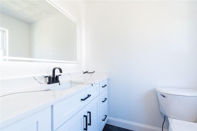 half bath featuring toilet, vanity, and baseboards