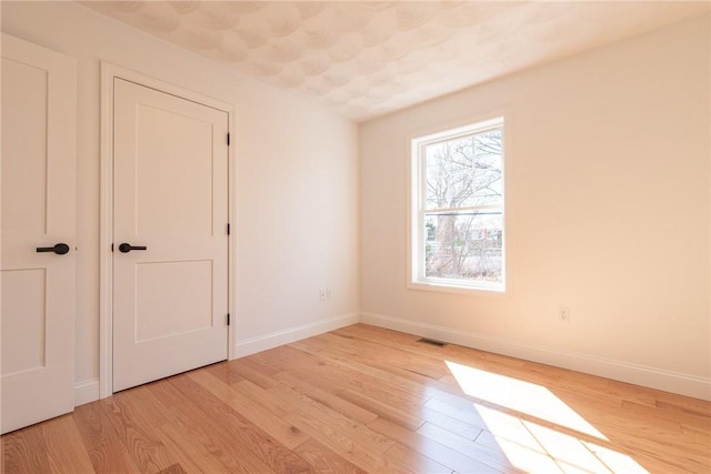 unfurnished bedroom with baseboards, light wood-type flooring, and visible vents