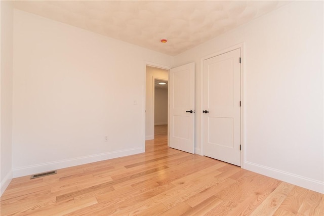 empty room featuring visible vents, baseboards, and light wood-style floors