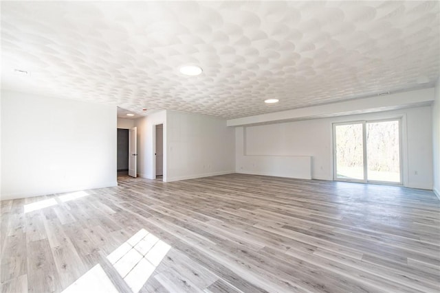 unfurnished living room with recessed lighting, light wood-style flooring, and baseboards