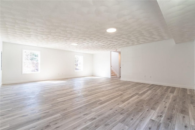 interior space featuring light wood-style floors, baseboards, and stairs