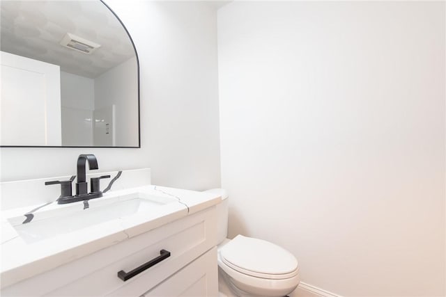 bathroom with toilet, visible vents, vanity, and baseboards