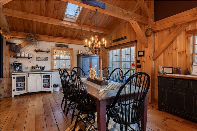 dining room featuring lofted ceiling with skylight, a chandelier, wood ceiling, and hardwood / wood-style floors