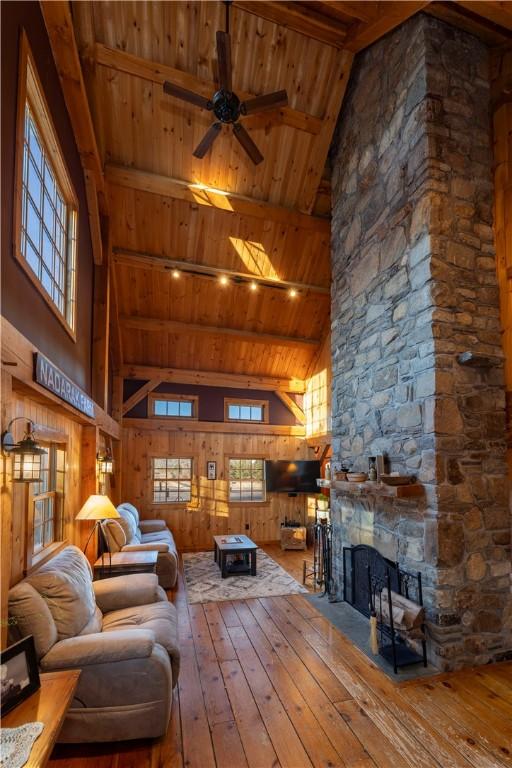 living room featuring wood walls, hardwood / wood-style floors, beam ceiling, a fireplace, and wooden ceiling