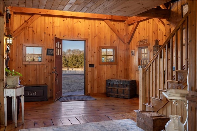 entrance foyer featuring hardwood / wood-style flooring, wooden walls, wooden ceiling, lofted ceiling, and stairs