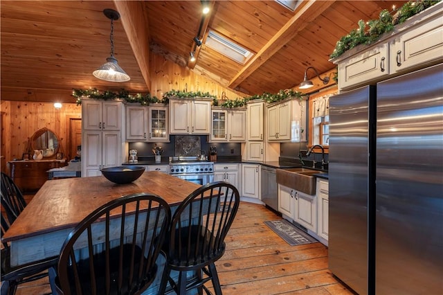 kitchen featuring light wood-type flooring, a sink, dark countertops, stainless steel appliances, and wooden ceiling