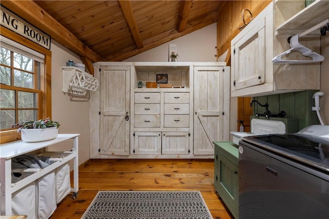 kitchen with wooden ceiling, light wood-style flooring, vaulted ceiling with beams, and washing machine and dryer