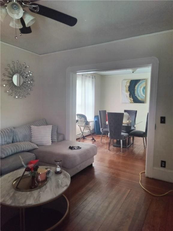 living area with baseboards, ceiling fan, and wood finished floors