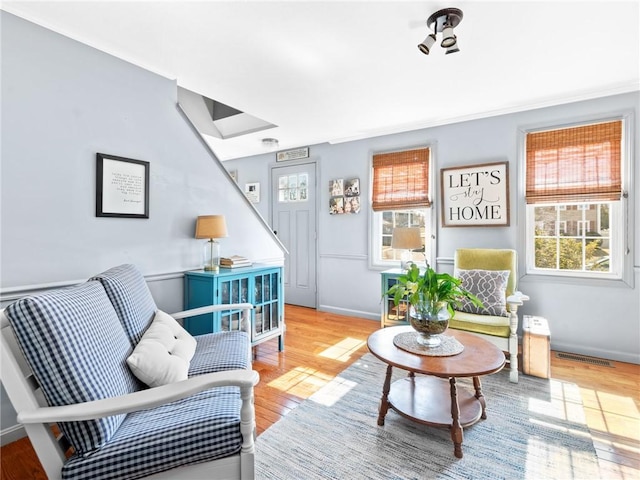 living area with wood finished floors, visible vents, a wealth of natural light, and baseboards