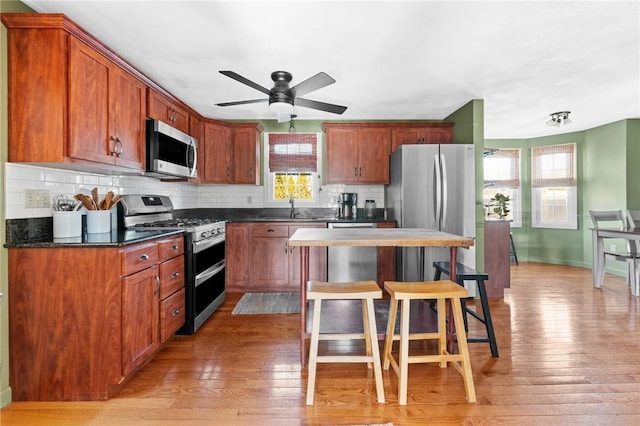 kitchen featuring a sink, light wood-style flooring, appliances with stainless steel finishes, and a breakfast bar