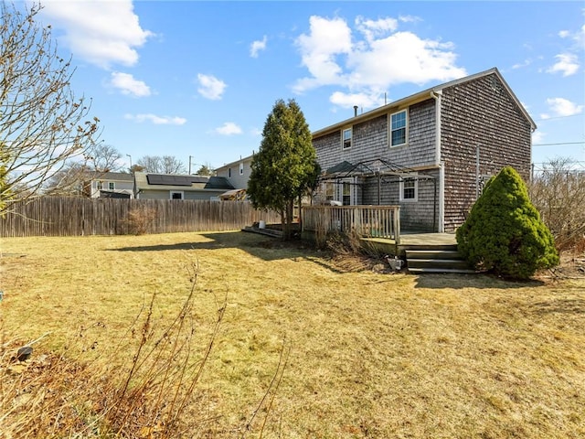 back of house featuring fence, a lawn, and a wooden deck