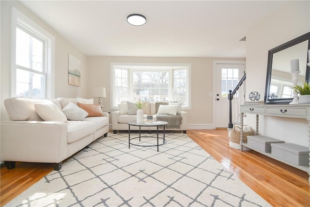 living area with stairway, light wood-type flooring, and a wealth of natural light