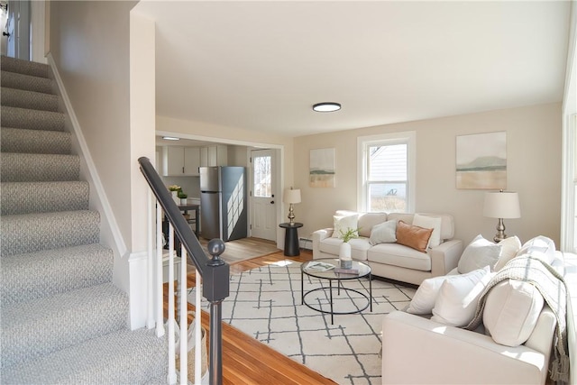 living room with light wood-type flooring, baseboards, and stairs