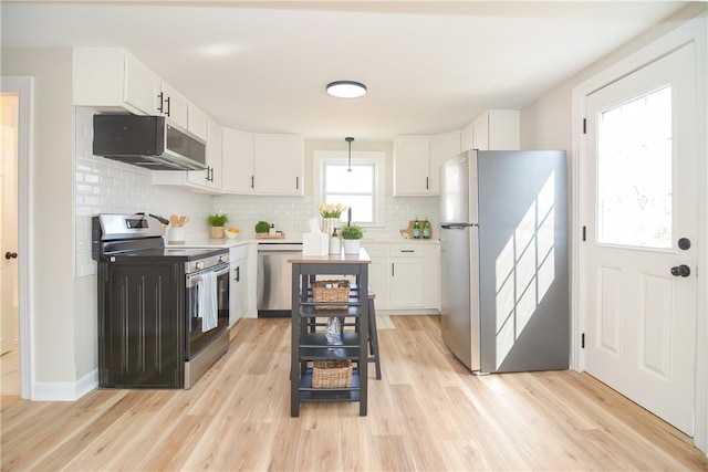 kitchen with light wood finished floors, stainless steel appliances, decorative backsplash, light countertops, and white cabinetry