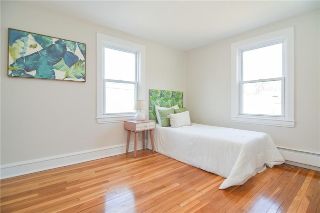 bedroom featuring light wood-style floors, baseboards, and baseboard heating