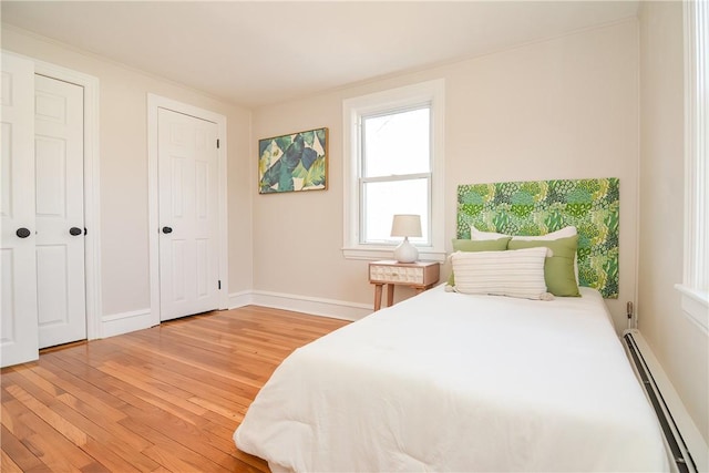 bedroom featuring baseboards, baseboard heating, and light wood finished floors