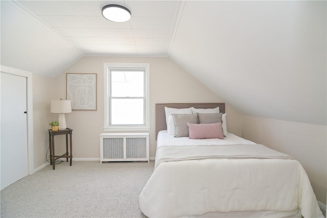 carpeted bedroom with baseboards, radiator heating unit, and vaulted ceiling