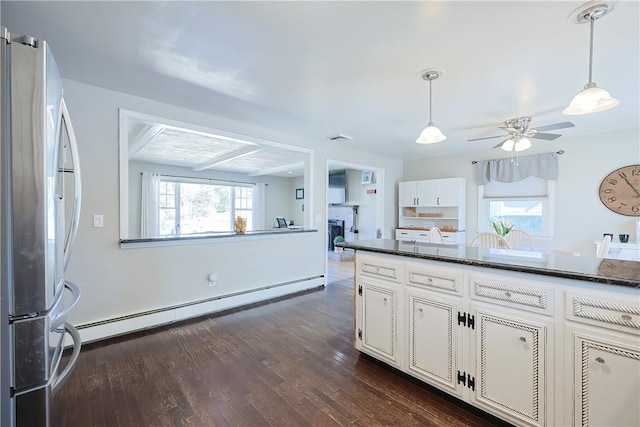 kitchen featuring dark wood-type flooring, a baseboard heating unit, freestanding refrigerator, white cabinets, and hanging light fixtures