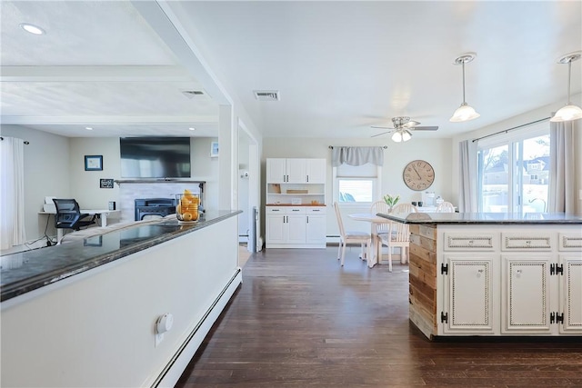 kitchen featuring visible vents, pendant lighting, dark wood-style floors, white cabinets, and a fireplace