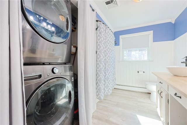 laundry area with visible vents, a sink, stacked washer / drying machine, baseboard heating, and laundry area