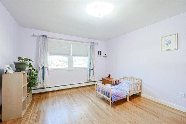 bedroom featuring baseboard heating, light wood-style flooring, and baseboards