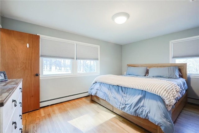 bedroom featuring light wood finished floors and a baseboard heating unit