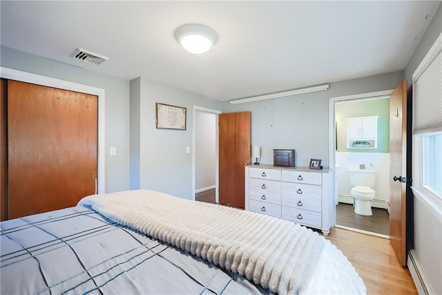 bedroom with light wood-style flooring, visible vents, a closet, and a baseboard radiator