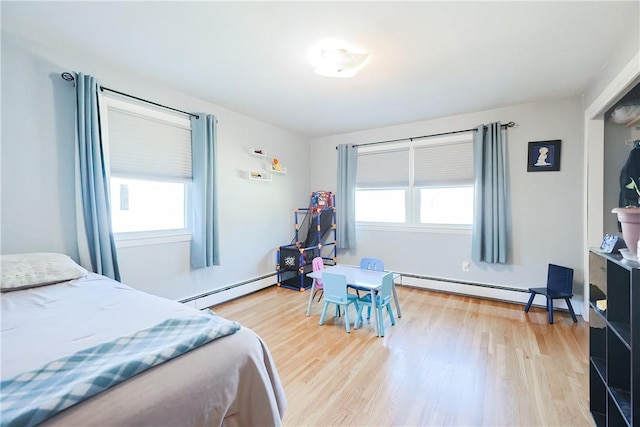 bedroom with a baseboard heating unit and wood finished floors