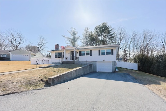 ranch-style house with an attached garage, a chimney, driveway, and fence