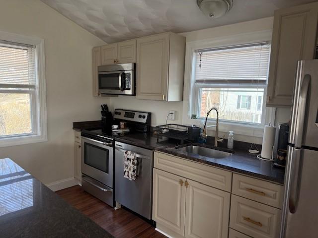 kitchen with dark wood-type flooring, a sink, white cabinetry, appliances with stainless steel finishes, and baseboards