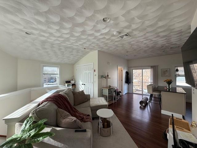 living room with dark wood-style floors, visible vents, and a textured ceiling