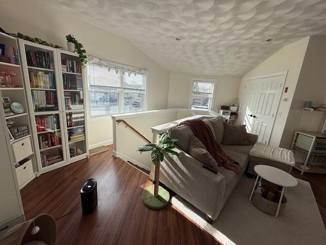 living room featuring a textured ceiling, lofted ceiling, and wood finished floors