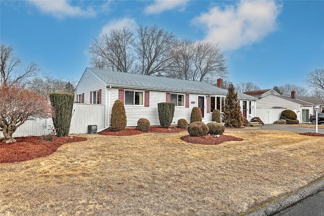 ranch-style home with a front lawn, fence, and a chimney