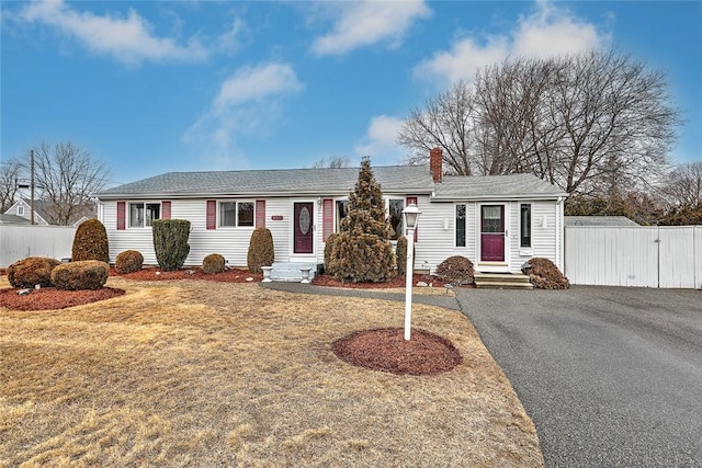 single story home featuring aphalt driveway, a gate, fence, and a front yard