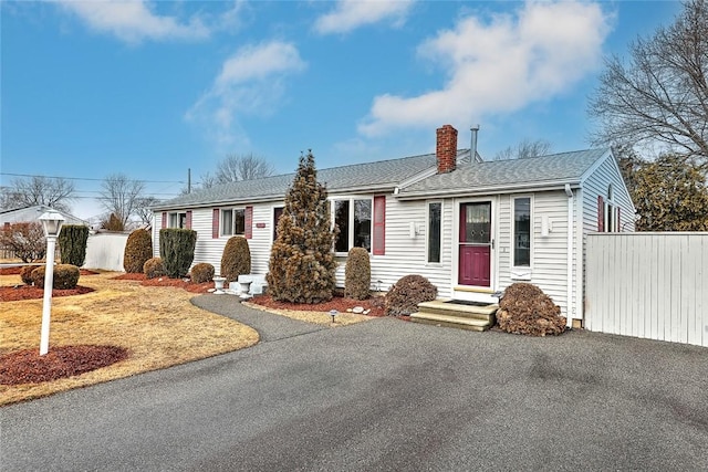 ranch-style home with fence, roof with shingles, and a chimney