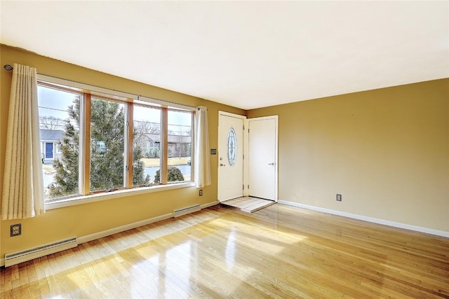 unfurnished room with light wood finished floors, baseboard heating, and baseboards