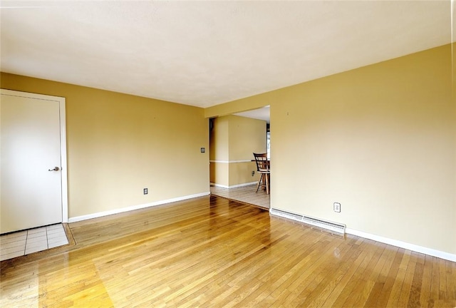 spare room featuring baseboards, baseboard heating, and light wood-style flooring