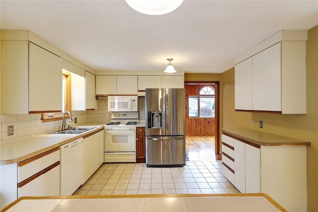 kitchen featuring white appliances, light tile patterned floors, tasteful backsplash, and a sink