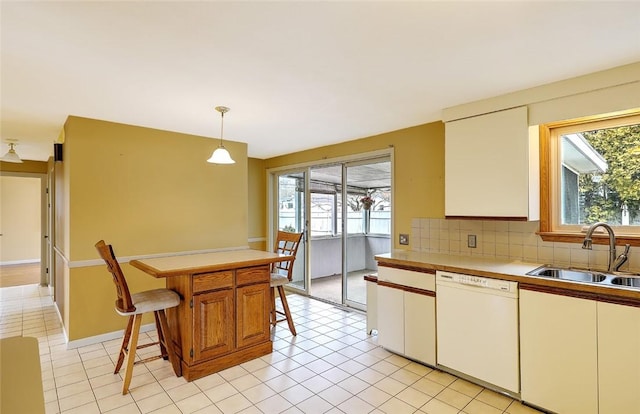 kitchen with a sink, a healthy amount of sunlight, white dishwasher, and light countertops