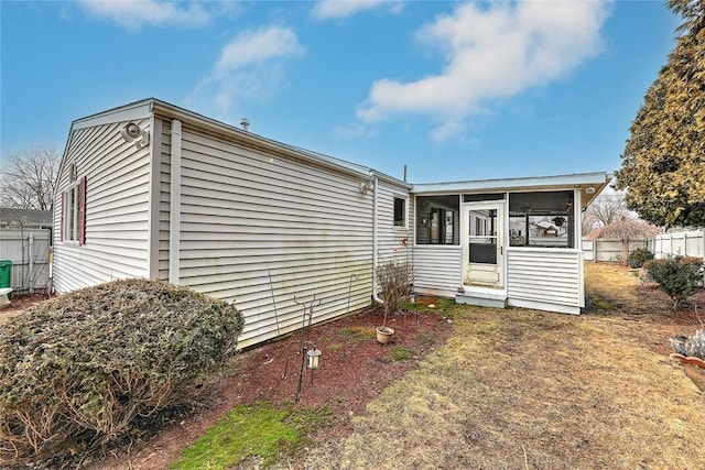 rear view of property featuring fence and a sunroom