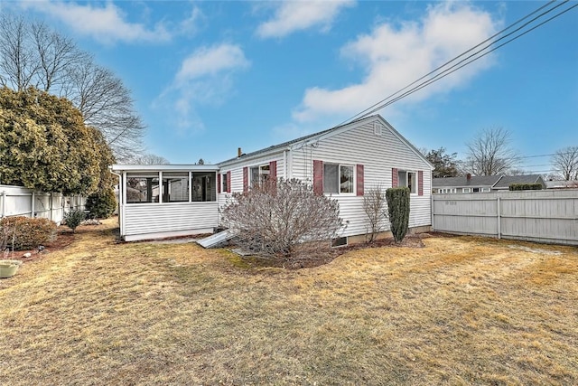 rear view of house featuring fence, a yard, and a sunroom