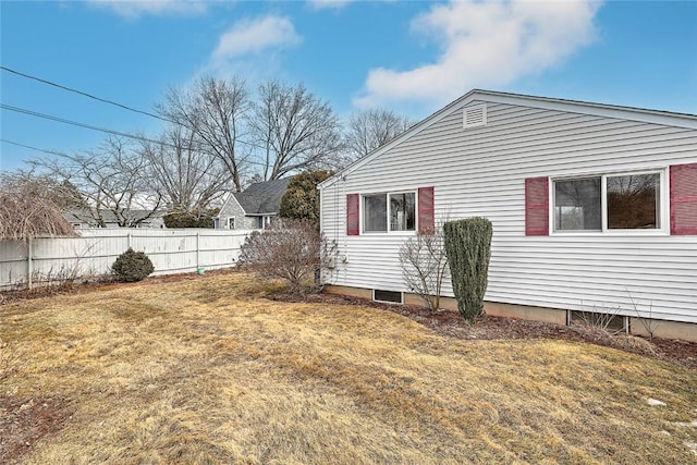 view of property exterior featuring fence and a lawn