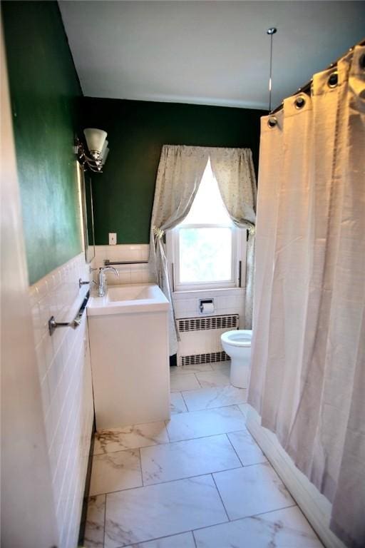 bathroom featuring radiator heating unit, wainscoting, tile walls, toilet, and marble finish floor