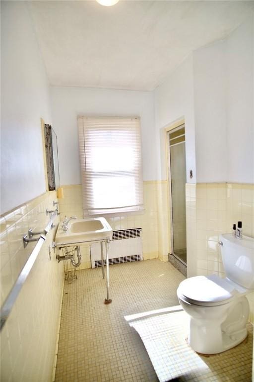 bathroom with tile patterned flooring, tile walls, radiator heating unit, and a stall shower